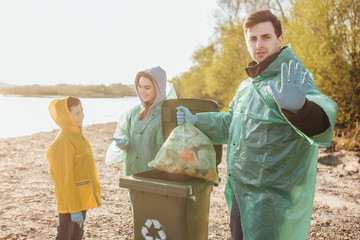 Handsome male  volunteer with his family garbage collection, near lake.