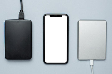Mobile phone mock up and removable hard drives on gray background.Storage and transfer of...