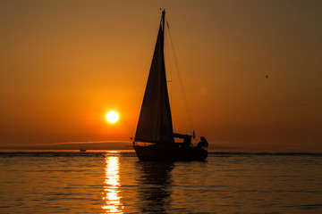 Fototapeta na wymiar yacht with a sail at sunset in the sea
