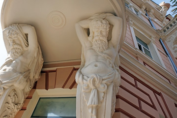 Male statues hold balconies. Beautiful white statues as a decoration of a building in a historic city building Not far from Europe Square.