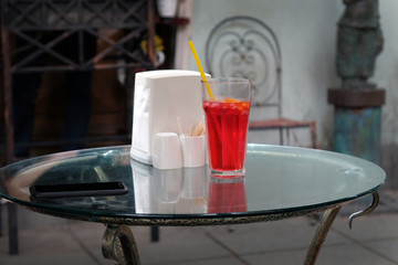 Berry lemonade in a transparent glass cup on a glass table in a cafe on the street. Refreshments in a cafe on the summer platform in Tbilisi.