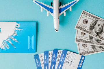 Passport, dollars, plane and air ticket on a blue background. Travel concept, copy space