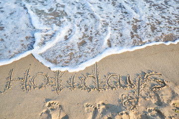 holiday word is written on the beach sand