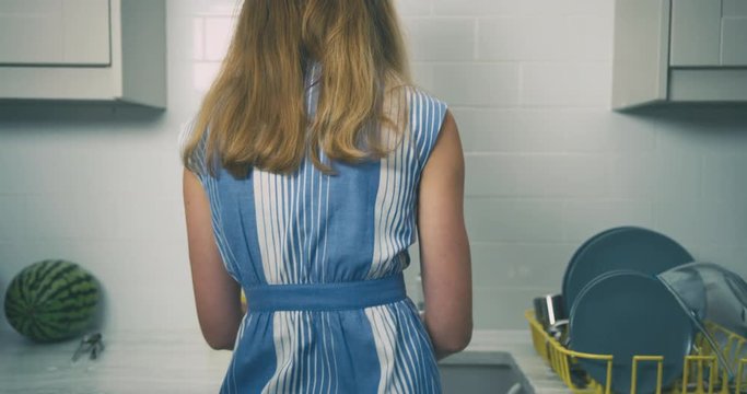 Young woman doing the dishes at the kitchen sink after dinner