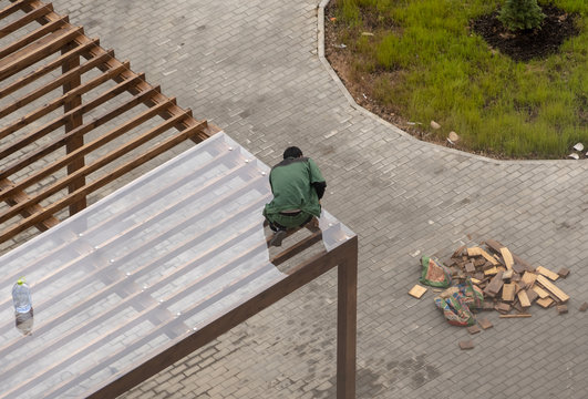 Worker In Green Overalls Mounts A Transparent Roof