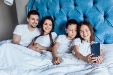 Focus at young family speak with grandmother with kids by phone, lying on bed..