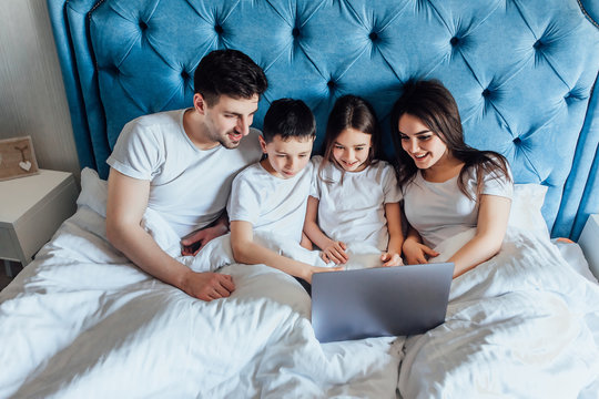 Portrait of family using laptop together in living room at home  in early morning.