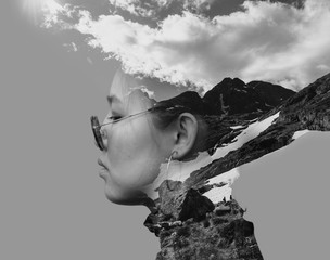 Black and white double exposure combined photographs with the Asian young woman wearing retro sunglasses and mountains.