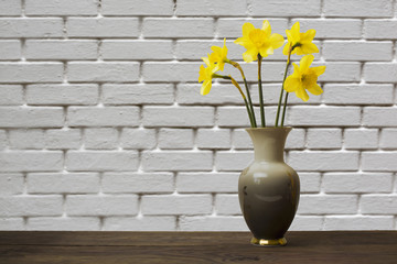 bouquet yellow narcissus flowers in a vase against a brick wall background