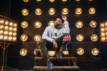 Black rapper in cap poses, perfomance on stage