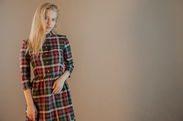 beautiful blonde with blue eyes in plaid dress touches her hair. Young actress shows acting exercises. woman actively expresses her emotions and poses for camera