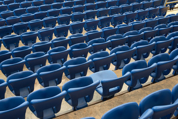 Fototapeta premium Rows of blue seats in the stand in the sports arena. One seat open and empty