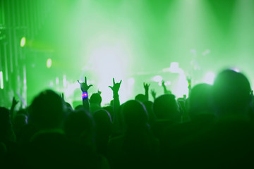 Concert, event or party concept. People with hands up at scene, spotlight, colored green light.
