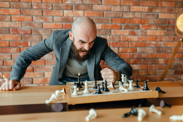 Angry chess player beats his fist on the board