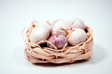 Garlic in a wicker basket, on a white background. Dried French garlic. Red garlic.