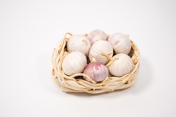 Garlic in a wicker basket, on a white background. Dried French garlic. Red garlic.