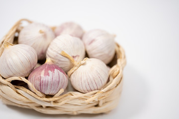 Garlic in a wicker basket, on a white background. Dried French garlic. Red garlic.