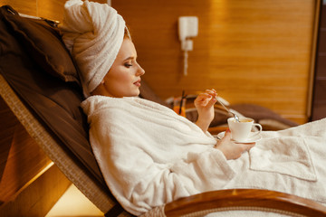 Sexy girl relaxing with cup of coffee in spa chair