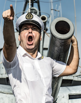 A Navy Officer Standing Beside Gun And Pointing His Finger Ahead.The Captain Issues An Order To Attack And Shoot From A Ship's Cannon.