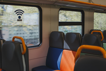 empty train carriage with multicolored seats and a sticker on the window WI-FI