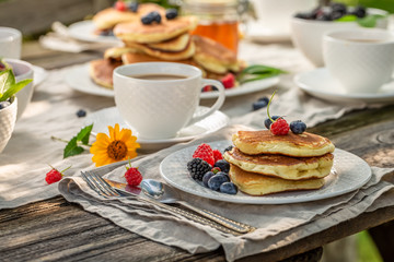 Pancakes with fresh berries and honey in summer garden