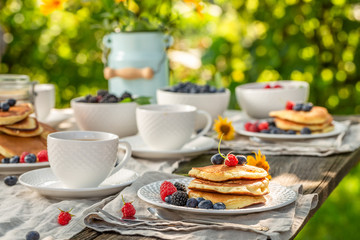 Delicious pancakes served with coffee in garden in summer garden