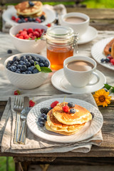 American pancakes with berries and honey in summer garden