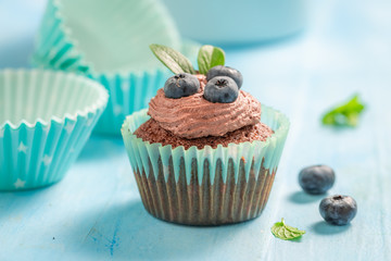 Cupcake made of chocolate cream and berries on blue table