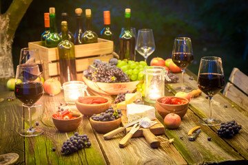 Closeup of table with snacks and wine in illuminated garden
