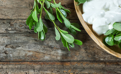 Fresh purslane (Portulaca oleracea), edible weeds with yoghurt on wooden table. Vegetable containing most Omega 3