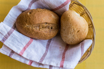 Fresh wheat buns in a basket on the table.
