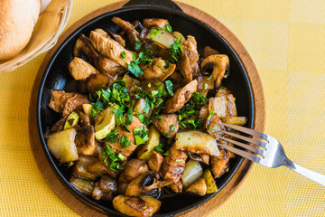 Potatoes with vegetables and meat, sprinkled with herbs and spices in a pan.