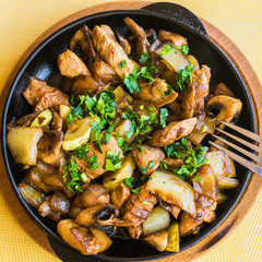 Potatoes with vegetables and meat, sprinkled with herbs and spices in a pan.