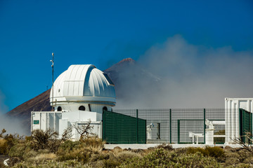 International observatory in Teide National Park. Volcano Teide on the backgriund. Windy day with clouds and amazinc colors. Technology science concept