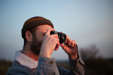 Close-up portrait of young guy taking photo by digital camera