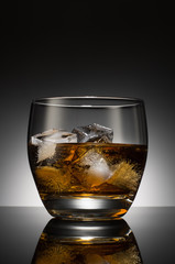 Whiskey with ice cubes in a glass on the background of a round black & white gradient