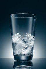 Water with ice cubes in a transparent blue glass on the background of a round gradient