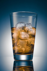 Iced tea with ice cubes in a transparent glass on the background of a round blue gradient.