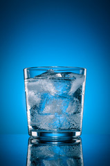 Transparent glass with water and natural ice cubes on the backgr