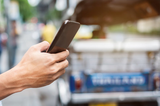 Young Man Tourist Or Casual Businessman Ordering Taxi Via Cab Application On Smartphone In City Street, Male Traveler Using Mobile Phone And Searching Direction On Digital Map At Bangkok, Thailand