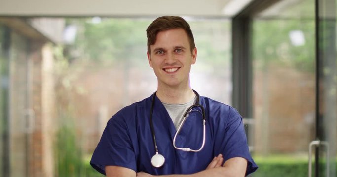 4K Portrait of happy & friendly male nurse in modern glass hospital building. Slow motion.