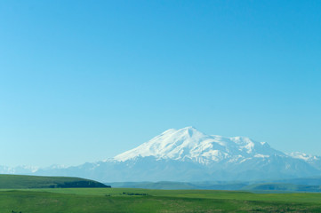 Fototapeta premium mount Elbrus in blue haze, view from Gumbashi pass