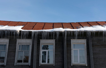 Icicles hang from the roof at the windows of the wooden house - Panorama HDR - High Dynamic Range