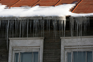 Icicles hang from the roof at the windows of the wooden house - Panorama HDR - High Dynamic Range