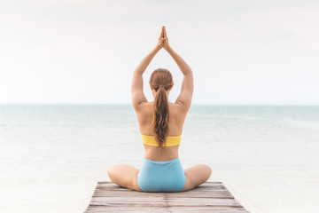 Fototapeta na wymiar Back of views woman practice yoga lotus pose to meditation summer vacation on pier with sea beach feeling so happiness and cheerful,Travel in tropical beach Thailand,vacations and relaxation Concept