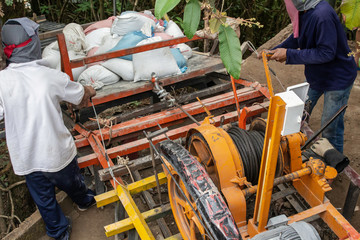 Construction workers are using electric winches to transport sandbags.