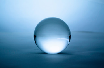 Crystal glass ball sphere transparent on blue gradient background.
