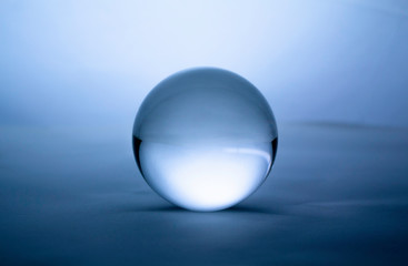 Crystal glass ball sphere transparent on blue gradient background.