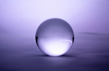 Crystal glass ball sphere transparent on purple gradient background.