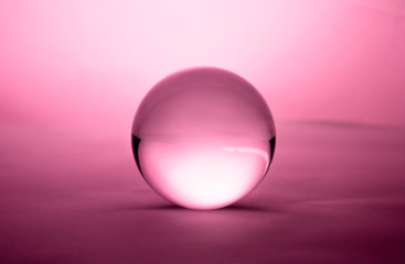 Crystal glass ball sphere transparent on pink gradient background.